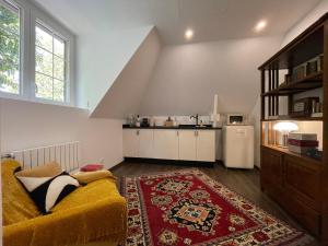 a living room with a yellow couch and a kitchen at La Maison Maya Normandie in Saint-Éloi-de-Fourques