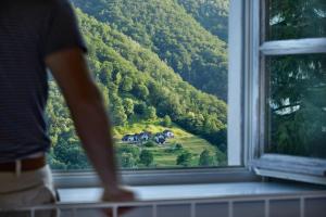 a person looking out of a window at a house at Villa Edera Exclusive Rental in Auressio