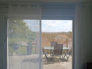 a sliding glass door to a patio with a table and chairs at Charmante maison à louer in Lagor