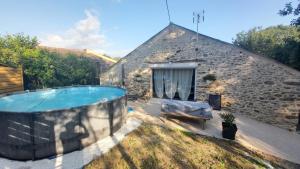 a large swimming pool in a yard next to a stone building at La Grange du Pradel in Montredon-Labessonnié