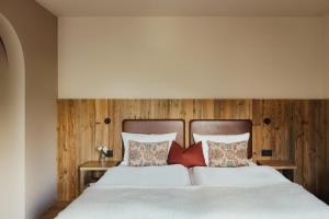 a bedroom with a bed with white sheets and red pillows at Albergo Stella in La Villa