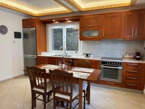 a kitchen with wooden cabinets and a table with chairs at Leka Village Our Hidden Gem in Léka