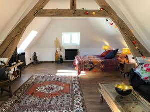 a attic room with a bed and a rug at La Maison Maya Normandie in Saint-Éloi-de-Fourques