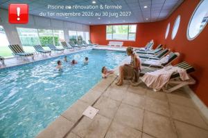 a woman sitting in a swimming pool with people in it at Hôtel Beau Rivage in Gérardmer