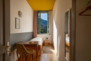 a room with a table and a bed and a window at Wild Valley Hostel - Villa Edera in Auressio