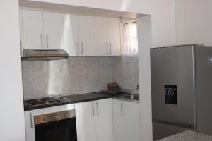 a kitchen with white cabinets and a stainless steel refrigerator at Thami residence - Self catering in Grahamstown +25 photos