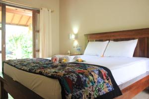 a bedroom with a large white bed with a window at Toke Menjangan in Banyuwedang