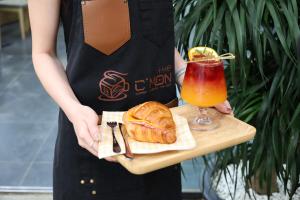 a woman holding a tray of food and a drink at The C'mon Mộc Châu in Làng Môn