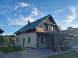 a small white house with a gambrel roof at Apartament Blisko Lasu in Rzystnowo