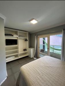 a bedroom with a large bed and a large window at pousada das manas in Torres