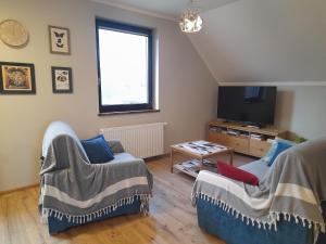 a living room with two chairs and a tv at Apartament Blisko Lasu in Rzystnowo