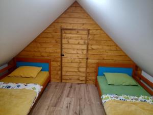 two beds in a room with wooden walls at Apartament Blisko Lasu in Rzystnowo