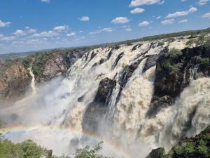 a rainbow in front of a waterfall at Ruacana Guest House in Ruacana