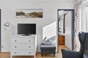 a living room with a tv on a dresser and a chair at Ferienwohnung Kleine Auszeit Nr 3 in Maasholm