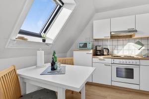 a kitchen with white cabinets and a white table at Ferienwohnung Kleine Auszeit Nr 3 in Maasholm