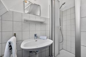 a white bathroom with a sink and a mirror at Ferienwohnung Kleine Auszeit Nr 3 in Maasholm +10 photos