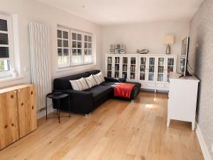 a living room with a black couch and wooden floors at Ferienhaus in Graal-Müritz in Graal-Müritz