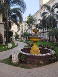 a fountain in a park with palm trees and a building at Leela Homes - Backpacker's Nest in Arpora