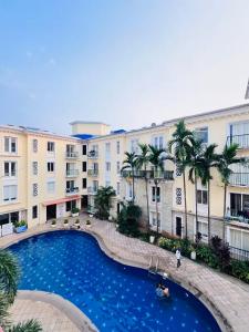 a large pool in front of a building with palm trees at Leela Homes - Backpacker's Nest in Arpora