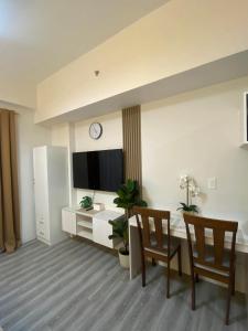 a living room with a table and two chairs and a television at Iam Cozy Condo Mactan Airport in Lapu Lapu City