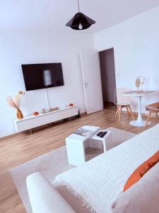 a white living room with a tv and a table at Le Terra Rosa - Proche Zoo & Lac de la ramée in Plaisance-du-Touch