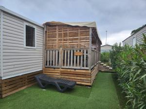 a wooden house with a bench next to a building at Camping Siblu Mar Estang le paradis des anges in Canet-en-Roussillon