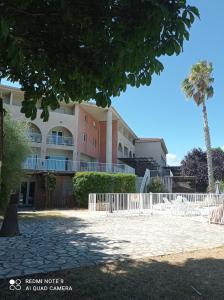 a building with a fence and a palm tree at résidence la citadelle in Saint-Florent