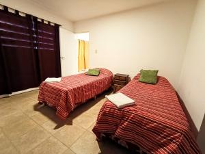 a bedroom with two beds with red and green blankets at La Morenita dos dormitorios in Chilecito