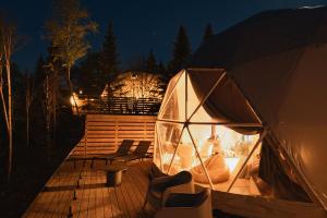 a tent with two chairs on a deck at night at Nørdika Charlevoix in Baie-Saint-Paul +48 photos