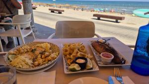 a table with two plates of food and a beach at Gladmar Apartment in La Mata