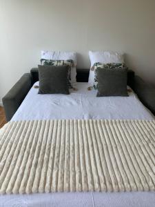 a large white bed with two pillows on it at Waterfront studio with small garden, pool, parking in Guidel