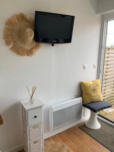 a living room with a chair and a tv on the wall at Waterfront studio with small garden, pool, parking in Guidel
