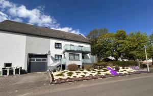 a white house with a flower bed in front of it at Ferienwohnung Lena in Morbach