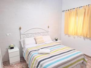a bedroom with a bed with a colorful striped blanket at las olas in Chipiona