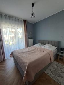 a bedroom with a large bed and a large window at E&M-Plażowa in Międzywodzie