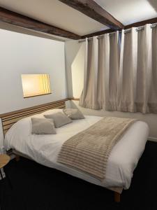 a bedroom with a large white bed with curtains at Hotel La Basilique in Épinal