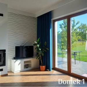 a living room with a tv and a sliding glass door at Apartamenty Ku Dolinie in Wilków