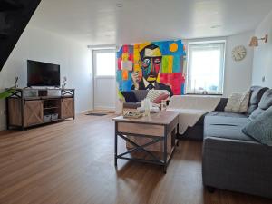 a living room with a couch and a painting on the wall at gîte 6 personnes le cocon des pommes in Saint-Lambert-et-Mont-de-Jeux