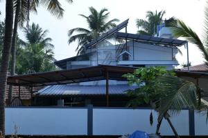 a building with palm trees in front of it at Velankanni Home Stay in Mangalore