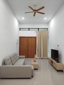 a living room with a couch and a ceiling fan at 4 Seasons Homestay in Kuantan