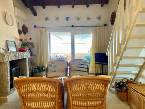 a living room with two wicker chairs and a staircase at Punta Est - Trilo LAVANDA Terrazza & Piscina in Capo Coda Cavallo