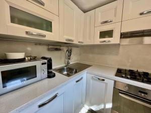 a kitchen with white cabinets and a sink and a microwave at Punta Est - Trilo LAVANDA Terrazza & Piscina in Capo Coda Cavallo