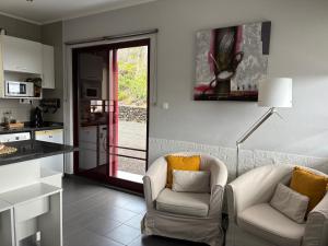 a living room with two chairs and a kitchen at Vista Montanha in Madalena