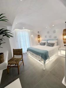 a white bedroom with a bed and a chair at Naxos Cave Suites in Stelida +196 photos