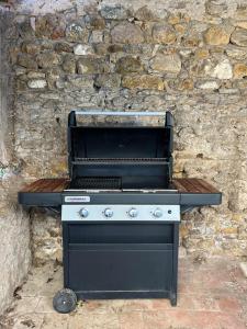 a black and white grill in front of a stone wall at Gîte Chez Mamie Madeleine in Ainay-le-Château