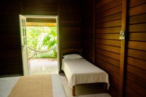 a small room with two beds and an open door at Pousada Coco Dendê in Ilha de Boipeba