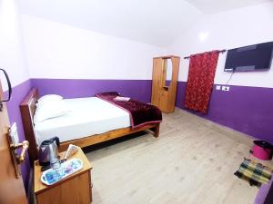 a small room with a bed and a tv at Ooty Gate Residency in Ooty
