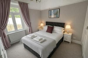 a bedroom with a bed with two lamps and two windows at Ferndale Lodge in Torquay