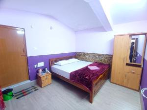 a small bedroom with a bed and a cabinet at Ooty Gate Residency in Ooty