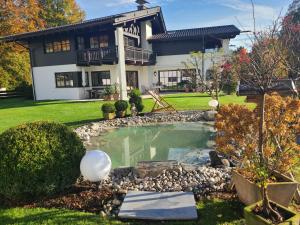a house with a pond in the yard at Frühholz - Das Ferienhaus - in Grainau